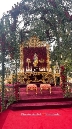 the altar is decorated with red flowers and greenery, along with gold benches for seating