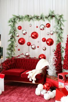 a living room decorated for christmas with red couches and ornaments on the wall behind it