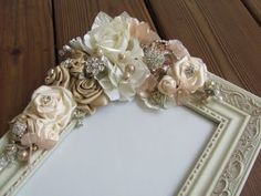 a white frame with flowers and pearls on the edges is sitting on a wooden table