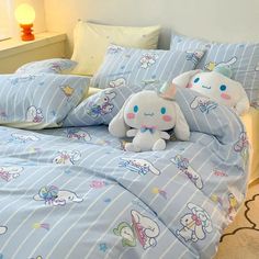 two stuffed animals sitting on top of a bed with blue sheets and striped comforters