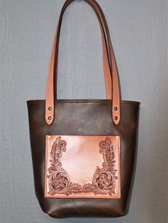 "The Medium Ladies Tote is part of my new Professional Cowboy Series. It measures 12\"x14\" and is made from high quality chap leather with a smooth, soft, pull-up finish. It features a Hermann Oak front pocket measuring 8\"x9\" that is hand tooled with a floral and feather pattern. The handles measure 3 feet in length and 1\" wide and are made from Hermann Oak skirting, lined with Hermann Oak, and attached with heavy duty brass rivets. Customization is also available including colors, initials, Handmade Leather Tote Bag, Handmade Leather Tote, Feather Pattern, Pull Up, Womens Tote, Handmade Leather, Leather Tote Bag, Large Bags, Leather Craft