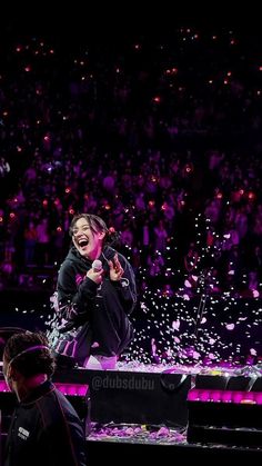 a woman standing on top of a stage with confetti falling from her hands