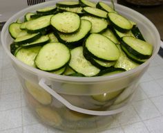 a bucket filled with sliced cucumbers sitting on top of a counter next to a microwave