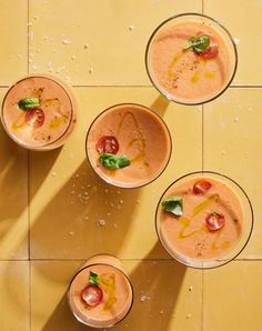 four glasses filled with different types of food on top of a yellow tile floor next to each other