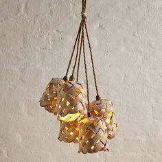 three woven lights hanging from a rope on a white wall with no one around them