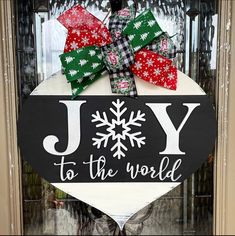 a sign that says joy to the world hanging on a door with snowflakes