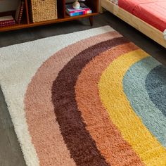 a multicolored rug on the floor next to a bed