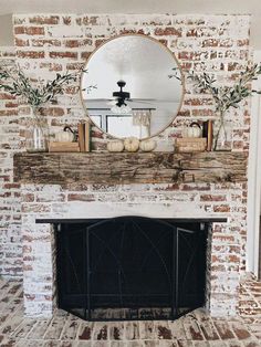 a fireplace with a mirror above it and some plants in front of the fire place