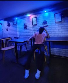 a person sitting at a table in a room with blue lights on the walls and chairs