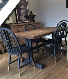 a dining room table with four chairs and an old dresser in the corner under stairs