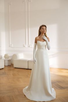 a woman in a white wedding dress posing for the camera with her hand on her face