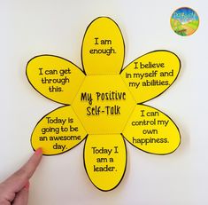 a hand pointing at a yellow flower with words on it