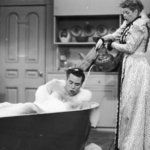 an old black and white photo of two people in a bathtub