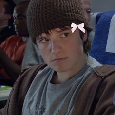 a young boy wearing a beanie with pink bows on it's head and looking at the camera