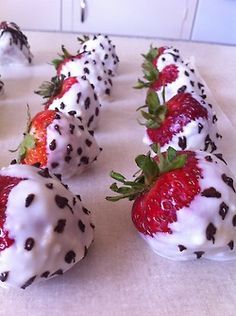 chocolate covered strawberries with white frosting and sprinkles on a table