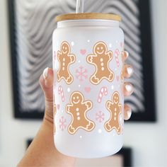 a woman holding up a cup with a straw in it's mouth and decorated with gingerbreads