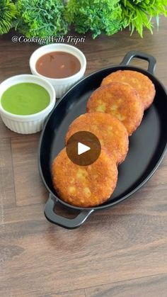 three fried food items on a black plate with dipping sauces