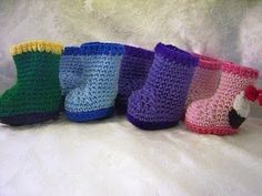 there are many crocheted boots lined up in a row on the white blanket