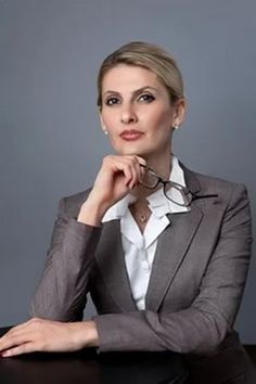 a woman is sitting at a desk with her hand on her chin and looking off to the side