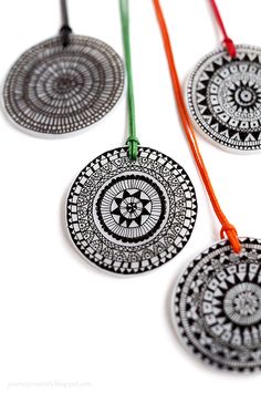 three black and white medallions with red string on the bottom one has an orange cord