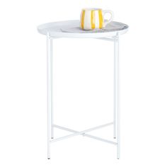 a white table with a yellow and white vase sitting on it's side shelf