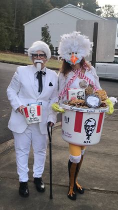 two people dressed in costumes standing next to each other holding buckets filled with food