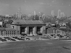 an old black and white photo of a large building in the middle of a city