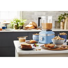 a blue blender sitting on top of a counter next to plates and bowls filled with food