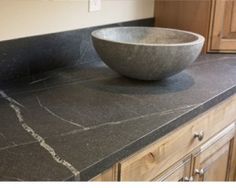 a bowl sitting on top of a counter in a room with wooden cabinets and drawers