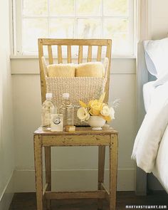 a wooden chair sitting in front of a window next to a table with bottles and soaps on it