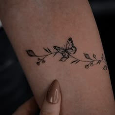 a woman's arm with a butterfly and flower tattoo on the left side of her arm