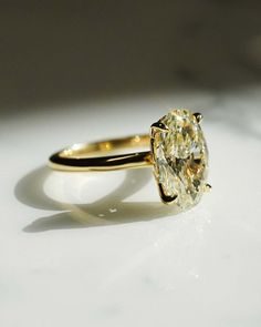 a yellow diamond ring sitting on top of a white table