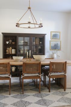 a dining room table with chairs and a chandelier hanging from it's ceiling