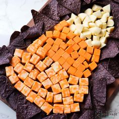 potato chips, cheese and carrots are on a platter with tortilla chips