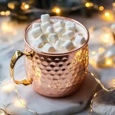 a copper mug filled with marshmallows on top of a table