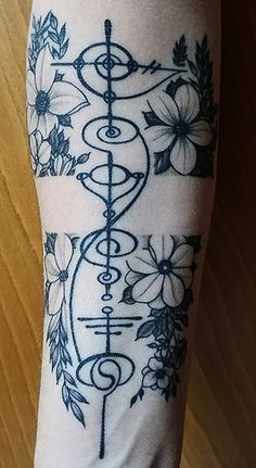 a person with a tattoo on their leg that has flowers and an arrow in the middle