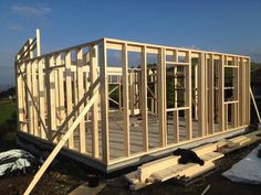 a house being built with wooden framing and roof trusss on the ground in front of it