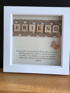 a white frame with the word friend spelled in scrabble letters and a butterfly