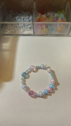 a bracelet with beads and charms sitting on top of a white cloth covered table next to plastic containers filled with candy