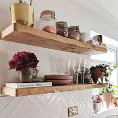 two wooden shelves filled with pots and glasses on top of a counter next to potted plants