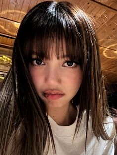 a close up of a person wearing a white shirt and long brown hair with bangs