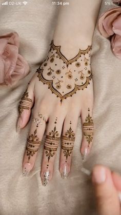 a woman's hands with hennap on top of her hand and flowers in the background