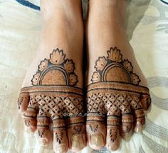 two feet with henna tattoos on them and one is showing it's intricate design