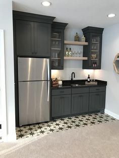 a kitchen with gray cabinets and black counter tops is shown in this image, there are lights on above the sink