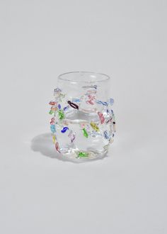 a clear glass with multicolored butterflies on the outside and inside, sitting on a white surface