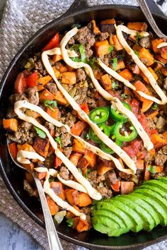 a skillet filled with meat and vegetables on top of a towel next to a fork