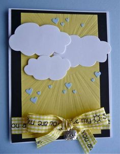 a greeting card with clouds and hearts on the front, tied in a yellow ribbon