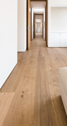 a long hallway with white walls and wooden floors is seen in this image from the front