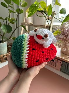 a hand holding a small stuffed animal in the shape of a fruit with a santa clause on it