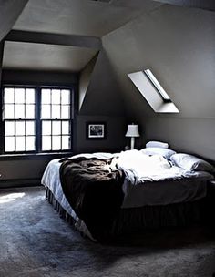 an attic bedroom with slanted ceilings and large bed in the center, along with two windows